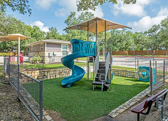 A playground with a blue slide and a yellow umbrella.
