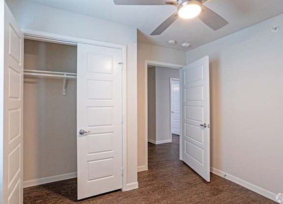 A room with a ceiling fan and two doors.