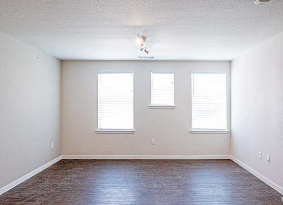 A room with two windows and a wooden floor.