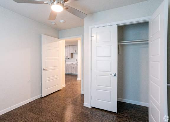 A room with a ceiling fan and two doors.