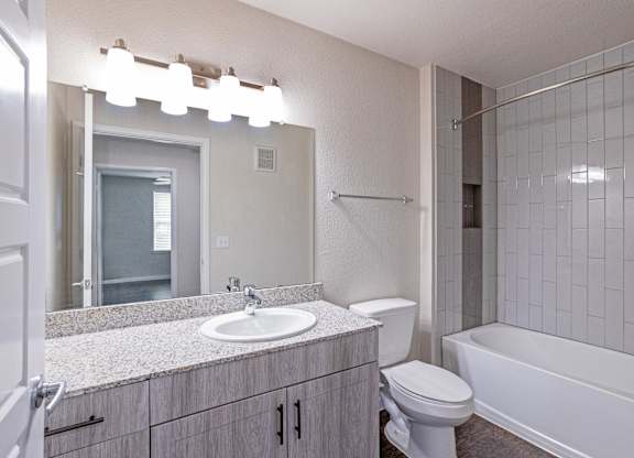 A bathroom with a white tub, sink, and toilet.