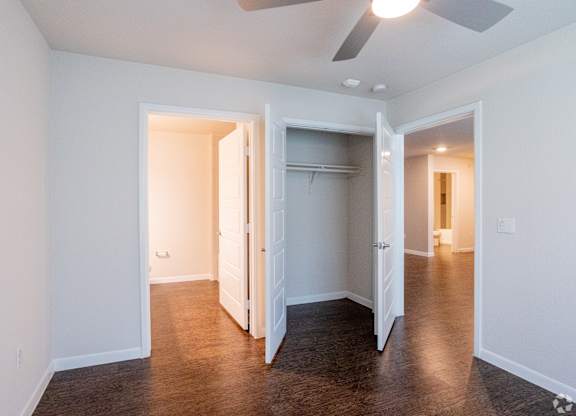 A room with a ceiling fan and a doorway leading to another room.