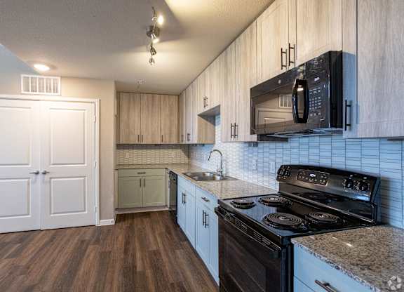 A kitchen with a black stove top oven and white cabinets.