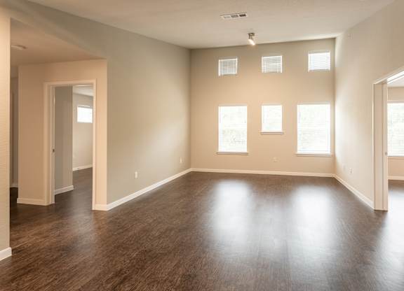 A large empty room with wooden floors and windows.