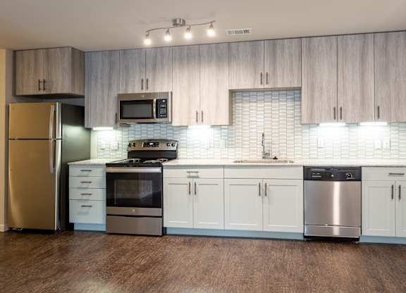 A kitchen with a refrigerator, stove, oven, and microwave.