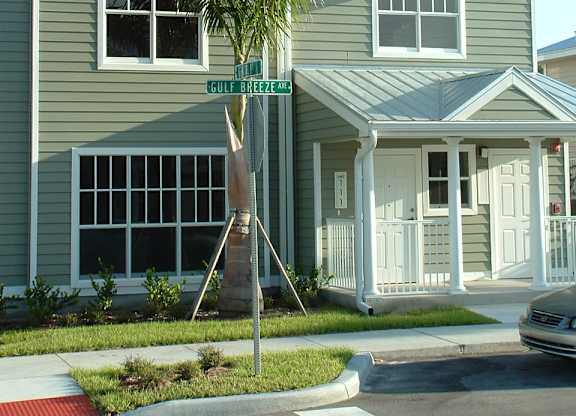 A grey two story house with a tree in front.