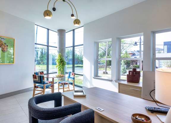 A room with a desk, chairs, and a painting on the wall.