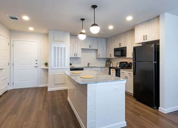 A kitchen with a black refrigerator and white cabinets.