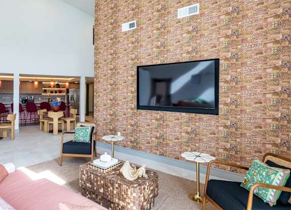 A living room with a brick wall and a flat screen TV mounted on it.