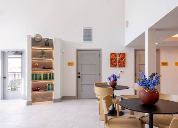 A dining area with a table and chairs and a vase of flowers.