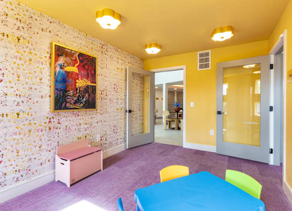 A room with a painting on the wall and a table with chairs.