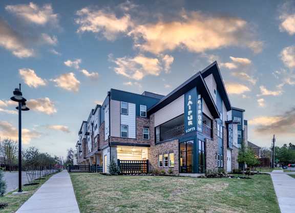 A modern apartment building with a well-maintained lawn in front.