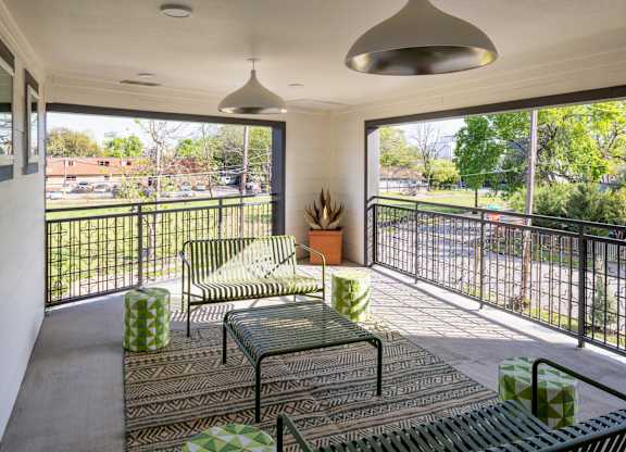 A balcony with a table and chairs overlooking a street.