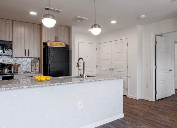 A kitchen with a white counter and a black fridge.