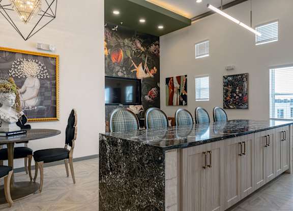 A kitchen with a black granite countertop and a painting of a woman holding a flower.