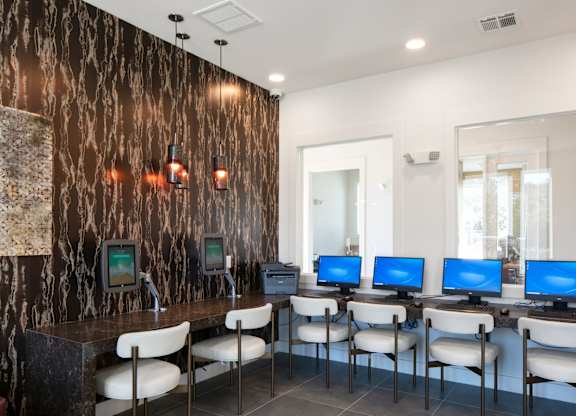 A room with a brown marble wall and a row of computers on desks.