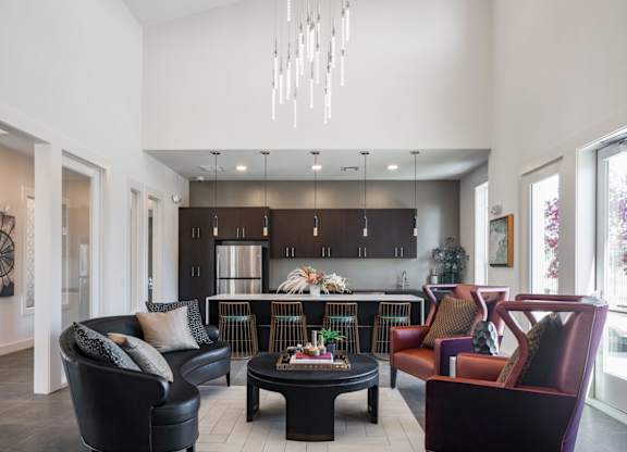 A modern living room with a black leather couch and a chandelier.