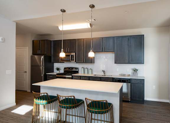 A kitchen with a white island and black cabinets.