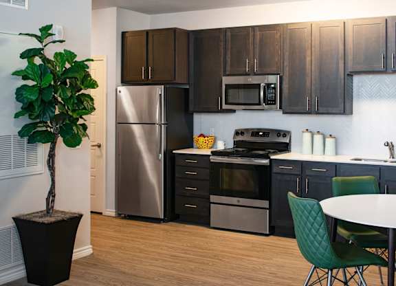 A kitchen with a stainless steel refrigerator, a microwave above the stove, and a dining table with chairs.