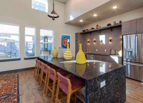 A kitchen with a black counter top and wooden chairs.