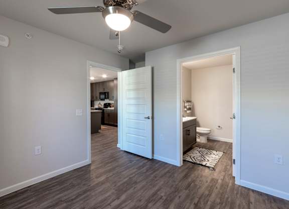 A room with a ceiling fan and a bathroom visible through an open door.
