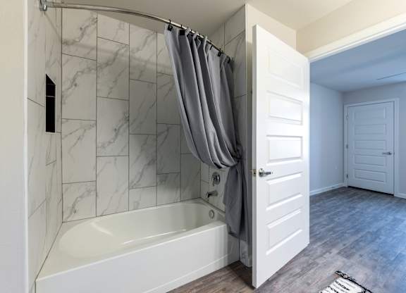 A white bathroom with a marble tiled shower.