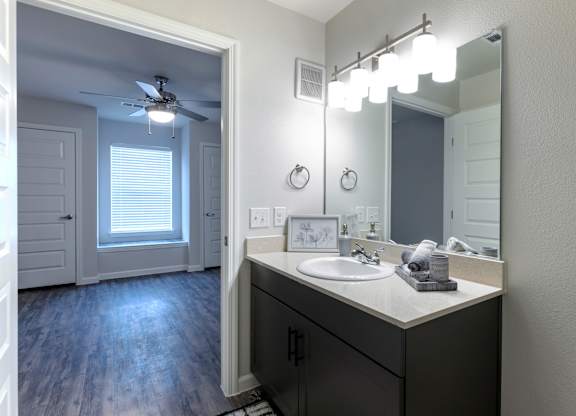 A bathroom with a sink, mirror, and lighting fixtures.