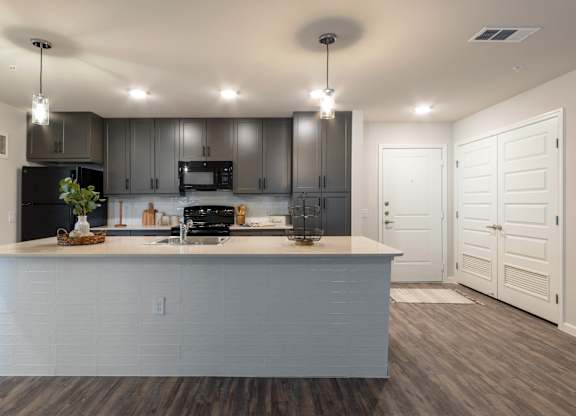 A modern kitchen with a large island and a black stove top oven.