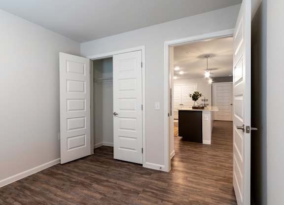 A room with white walls and a wooden floor with three white doors.
