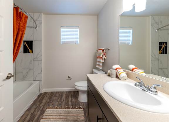 A bathroom with a white sink, toilet, and a shower with a red shower curtain.