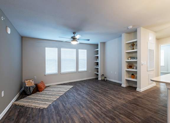 A room with a ceiling fan and wooden flooring.