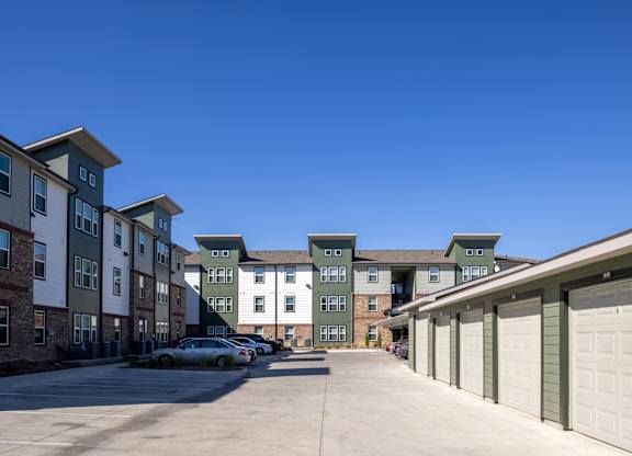 A row of garages in front of apartment buildings.