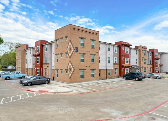 A parking lot in front of a multi-story apartment building.