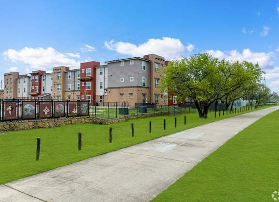 A long concrete pathway leads to a row of apartment buildings.