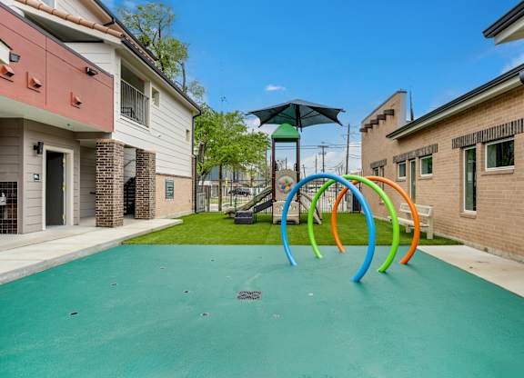 A playground with a green surface and colorful rings.
