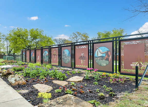 A garden with a fence and a signboard with pictures and text.