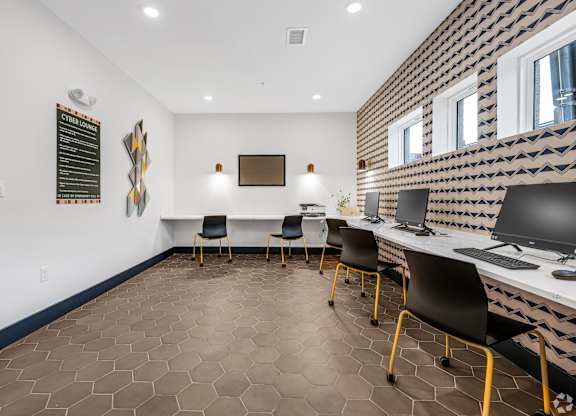 A room with a white desk and chairs with a patterned wallpaper on the wall.