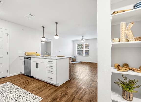 A kitchen with white cabinets and a wooden floor.