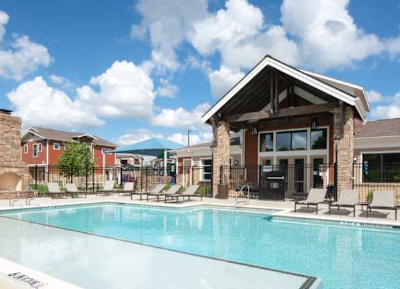 A swimming pool in front of a building with a covered patio area.