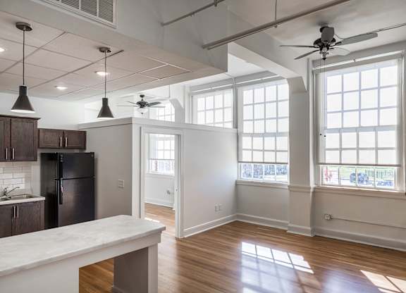 A kitchen with a refrigerator, cabinets, and a marble countertop.