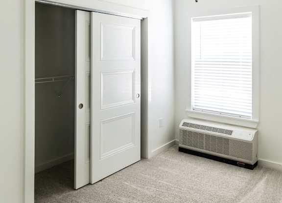 A room with a ceiling fan and a window with blinds.