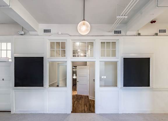 A room with white walls and a wooden floor with a white door on the left and a black door on the right.