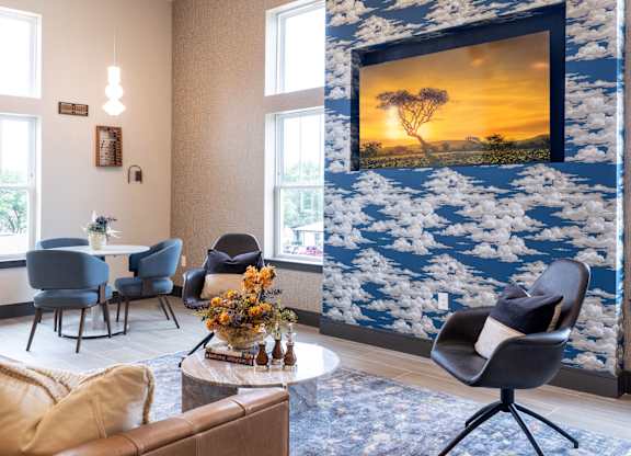 A living room with a large painting of a sunset on the wall.