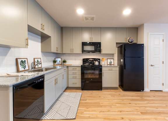 A kitchen with a black fridge and white cabinets.