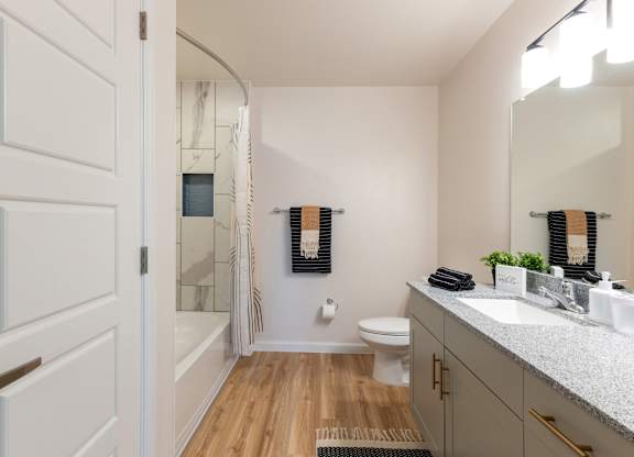 A white door is open to a bathroom with a toilet, sink, and mirror.