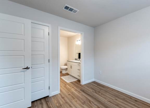 A white bathroom with a toilet, sink, and wooden floors.