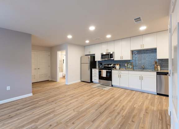 A kitchen with wooden floors and white cabinets.