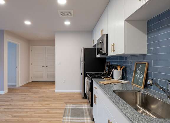 A kitchen with a black refrigerator and white cabinets.