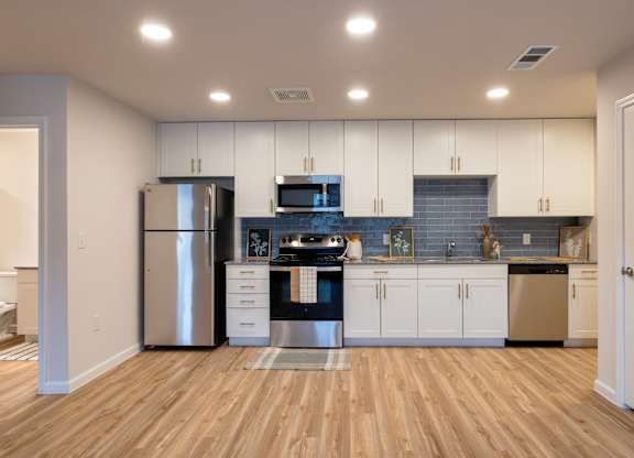 A kitchen with wooden floors and white cabinets.