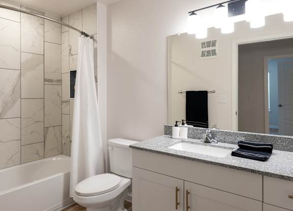 A white bathroom with a marble tile shower.